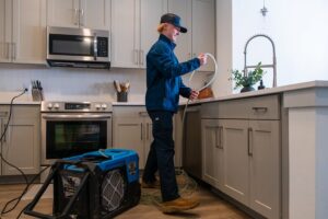 A RestoPros technician setting up water extraction equipment in a kitchen during a water damage restoration job in Lancaster, PA.
