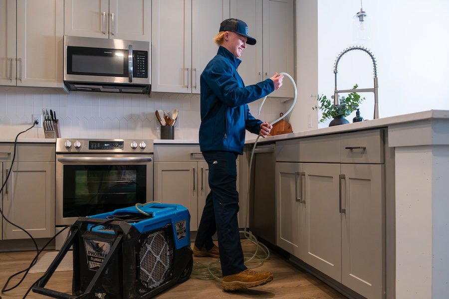 A RestoPros technician setting up water extraction equipment in a kitchen during a water damage restoration job in Lancaster, PA.