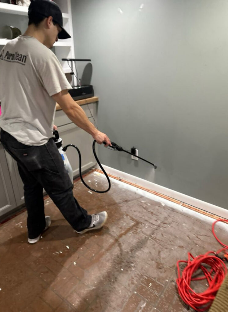 A PuroClean technician spraying disinfectant solution after water damage cleanup in Lancaster, PA.