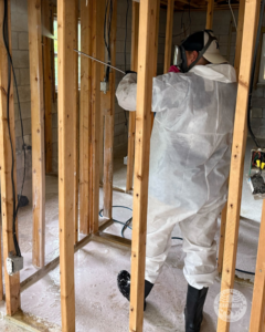 A technician spraying a solution on wall studs during water damage restoration for United Water Restoration Group of Omaha, NE.