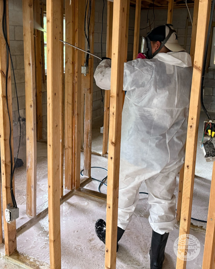 A technician spraying a solution on wall studs during water damage restoration for United Water Restoration Group of Omaha, NE.
