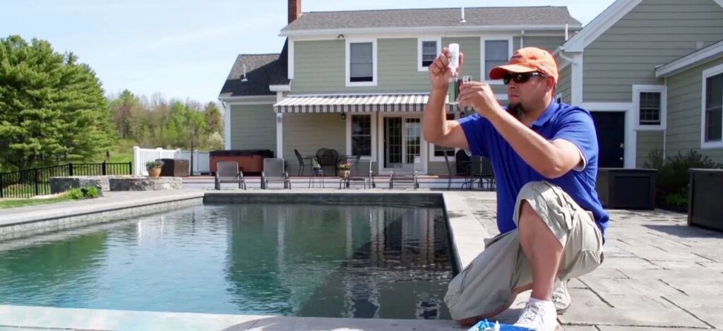 A pool technician performing water quality testing at a residential pool by Christman Pool Service in Portland, ME.