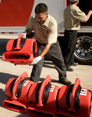 Technician unloading red air movers for water damage restoration by Belfor Property Restoration, New Orleans, LA