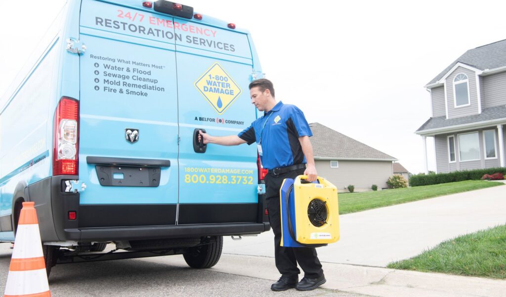 A technician from 1-800 Water Damage of Harrisburg, PA unloading water damage restoration equipment from a company van in York, PA.