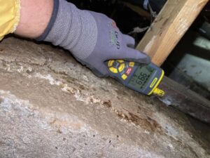 A technician using a moisture meter to assess water damage on a surface for APEX Restoration in Mililani, HI