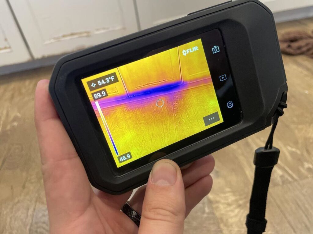 A technician using a thermal imaging camera to detect hidden moisture for APEX Restoration in Mililani, HI