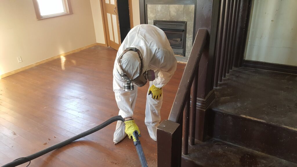 A Green Home Solutions technician in a hazmat suit performing water damage cleanup on a wooden floor in Mount Airy, MD.