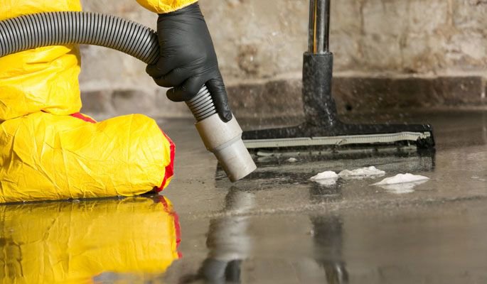 A technician in a hazmat suit performing water extraction with a wet vacuum after water damage by Water Damage Pro in Minneapolis, MN