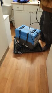 A technician standing next to a water damage dehumidifier in a bathroom during restoration by Robinson Restoration in Vancouver, WA