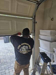 A Rebel Overhead Doors technician working on the bottom panel of a garage door during a service call in Las Vegas, NV.