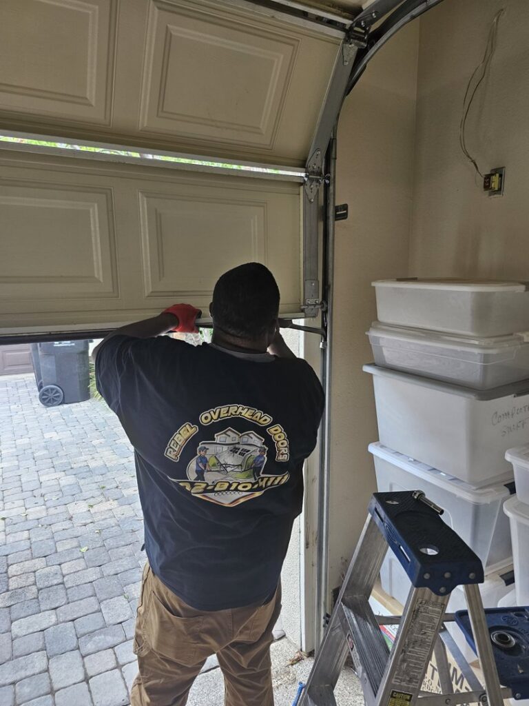 A Rebel Overhead Doors technician working on the bottom panel of a garage door during a service call in Las Vegas, NV.