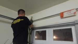 A Central Garage Door Service technician working on a garage door track and roller system in Kapolei, HI.