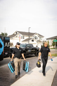 Two technicians carrying professional drying equipment to a water damage job site for APEX Restoration in Mililani, HI