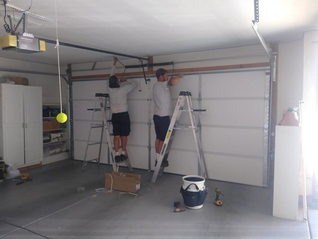 Two Garage Door Mesquite technicians on ladders performing installation or repair work on a residential garage door in Mesquite, NV.