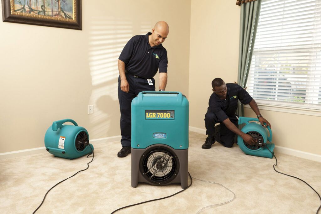 ServiceMaster technicians setting up professional drying equipment on a carpeted floor for water damage restoration in Lexington, KY.