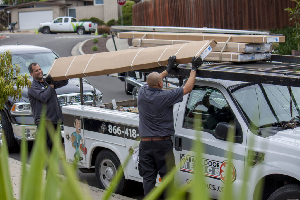 Garage Door Medics technicians unloading new garage door panels from a service truck in Boise, ID.