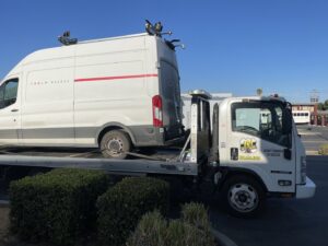 A white Tesla Energy van being transported on a flatbed tow truck by 101 auto towing inc in San Jose, CA.