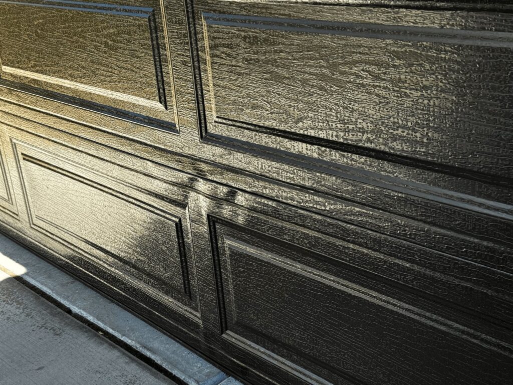 A close-up of a textured dark garage door panel, showcasing the detail of work by Apex Garage Doors LLC in Las Vegas, NV