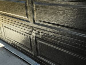 A close-up of a textured dark garage door panel, showcasing the detail of work by Apex Garage Doors LLC in Las Vegas, NV