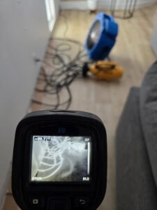 A thermal imaging camera used for water damage detection with drying equipment in the background by Emergency Flood Team in Gilbert, AZ