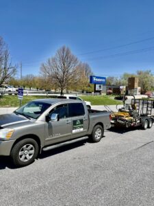 A Thompson Acres branded pickup truck pulling a trailer with professional lawn care equipment in Davenport, IA.