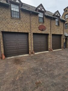 Three matching dark brown panel garage doors installed on a traditional brick building by 4thgenerationsdoors in Huntington, WV.