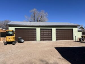 A building featuring three newly installed brown panel garage doors by Excellence Garage Doors LLC in Albuquerque, NM.