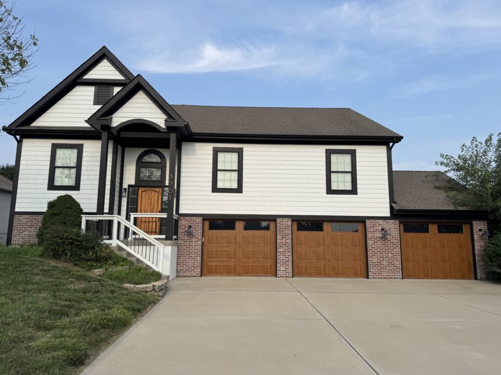 Three brown garage doors with decorative windows installed on a large home by ABC Garage Doors KC in Kansas City, KS.