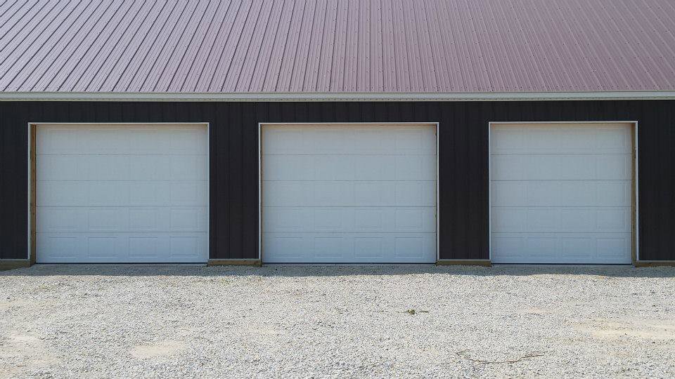 Three white commercial garage doors installed on a building by Cedar Valley Garage Doors in Waterloo, IA