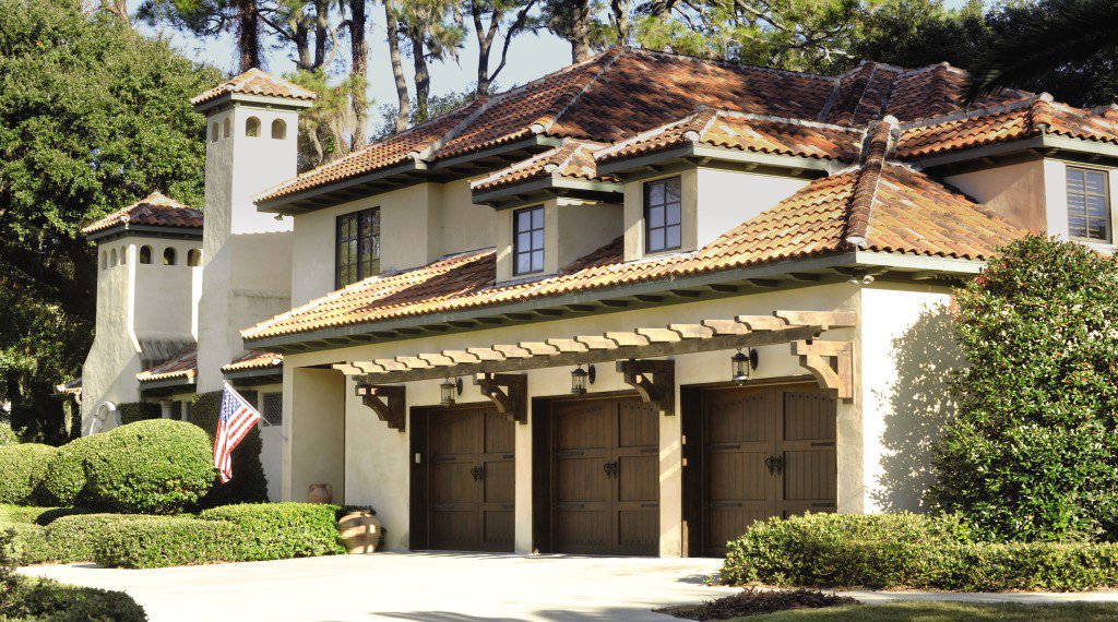 A luxurious home showcasing three dark wooden garage doors, installed by Overhead Door Co of Missoula in Missoula, MT.