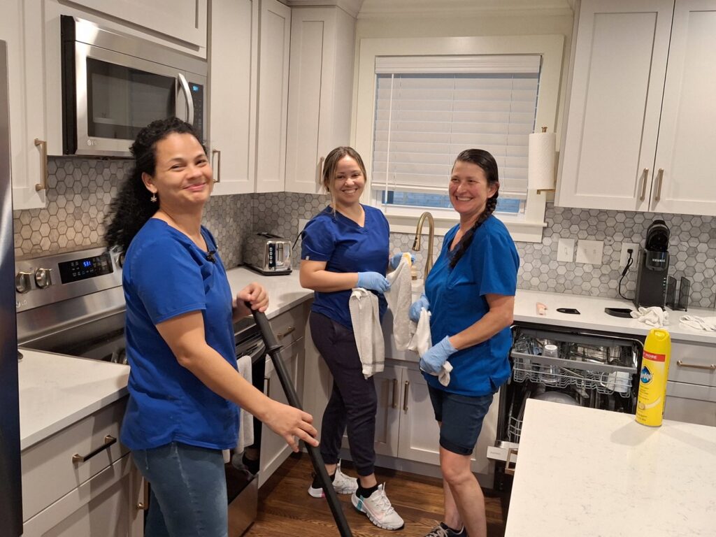 Three friendly house cleaners from Absolute Luxury, LLC Residential & Commercial Cleaning smile in a sparkling clean kitchen in Antioch, TN.