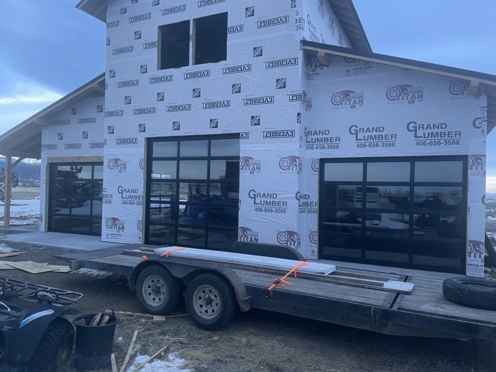 Three modern black glass garage doors installed on a new construction building by Elite Garage Door Service & Repair in Billings, MT.