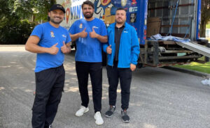 Three professional movers giving thumbs up next to a Let's Get Moving truck with its ramp down in Saint Petersburg, FL.