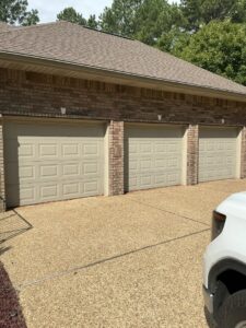 Three light beige panel garage doors installed on a brick house by Coney's Garage Doors in Conway, AR.