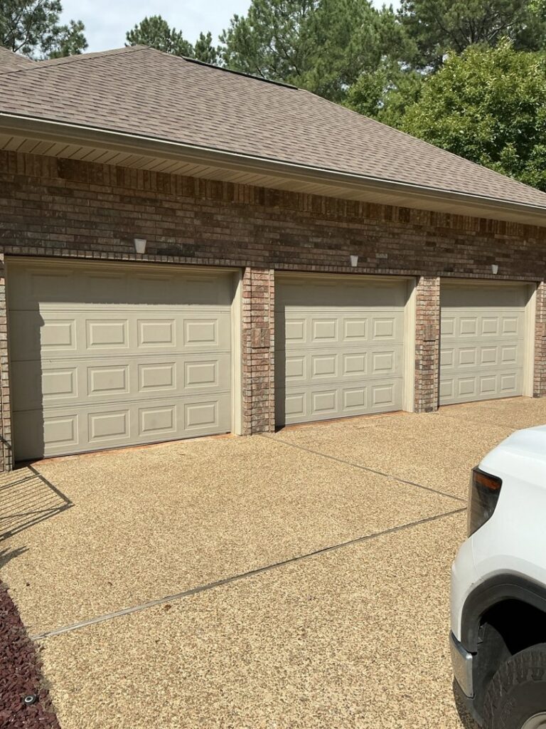 Three light beige panel garage doors installed on a brick house by Coney's Garage Doors in Conway, AR.