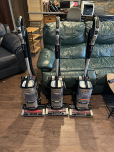 Three professional Shark vacuum cleaners lined up, ready for house cleaning by Wild Acre Home Services in Juneau, AK.