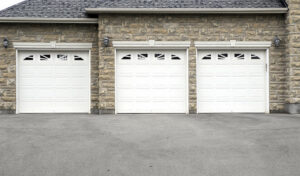 Three white garage doors with decorative windows installed on a stone house by K & B Door Co. in Las Vegas, NV