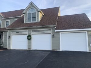Three white garage doors with top windows installed on a residential home by J.A. Overhead Door in Westfield, MA.