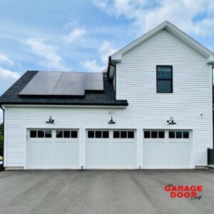 Three white panel garage doors with windows installed on a modern home by The Garage Door Guys, LLC in New Haven, CT.