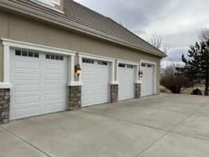 Three white paneled garage doors with decorative windows and stone accents, installed by Summit-Overhead-Door in Sparks, NV.