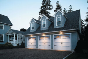 Three newly installed white residential garage doors on a blue house by Overhead Door Company of Mid-Ohio Valley in Parkersburg, WV.