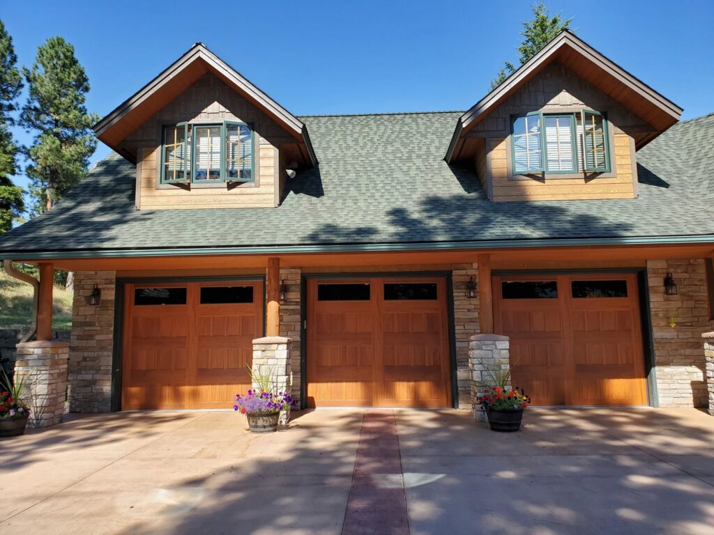 Three wood-look garage doors installed on a large residential home by Riverside Garage Doors in Kalispell, MT.