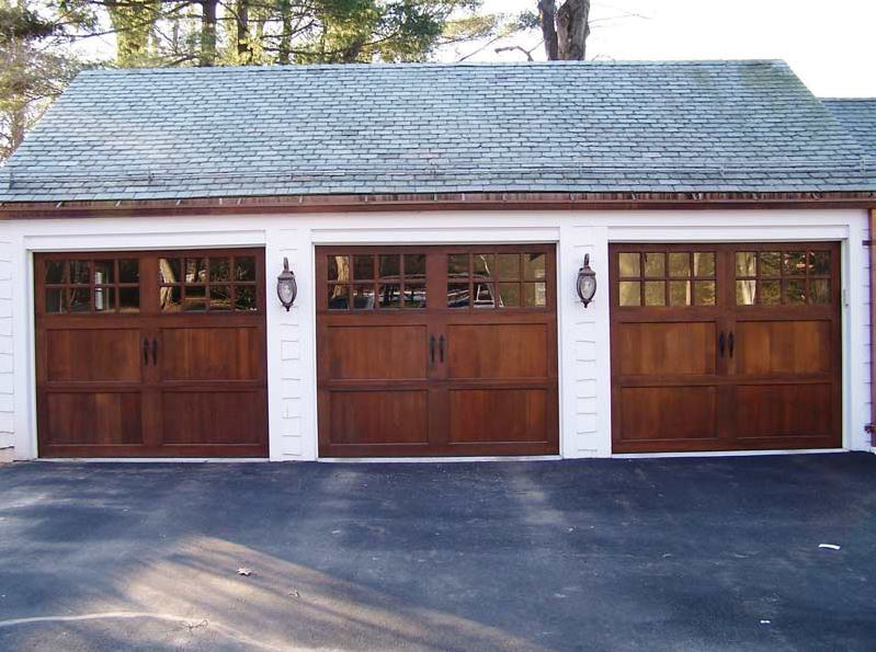 Three newly installed wooden garage doors with windows and decorative hardware by Douglas Garage Door Center in East Hartford, CT.