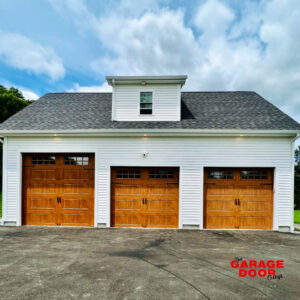 Three newly installed wooden-look garage doors with windows by The Garage Door Guys, LLC in New Haven, CT.