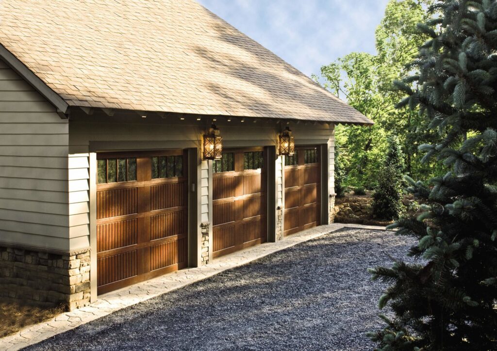 Three wooden-style garage doors on a residential property, installed by Access Door Systems in Uniontown, PA.