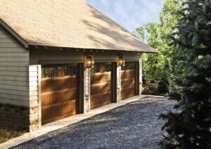 Three wooden-style garage doors on a residential property, installed by Access Door Systems in Uniontown, PA.
