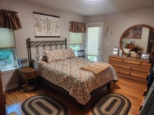 A neatly arranged bedroom with hardwood floors and a patterned bedspread, showcasing the tidiness achieved by E-N-S Home Cleaning Solutions, LLC in Lewiston, ID.