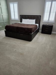 A neatly arranged bedroom with a made bed and clean carpeted floor, demonstrating the tidiness achieved by Carole's House Cleaning in Tempe, AZ.