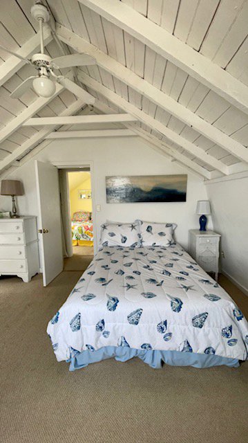 A tidy bedroom with a sloped ceiling and clean carpet, maintained by Straight Up Cleaning in South Portland, ME.