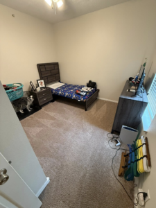 A tidy bedroom with a neatly made bed and vacuumed carpet, demonstrating cleaning by WWJM Cleaning Service in Oklahoma City, OK.